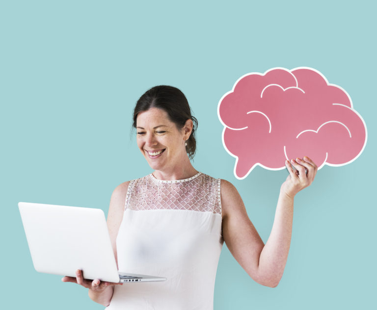 woman holding a brain icon and using a laptop